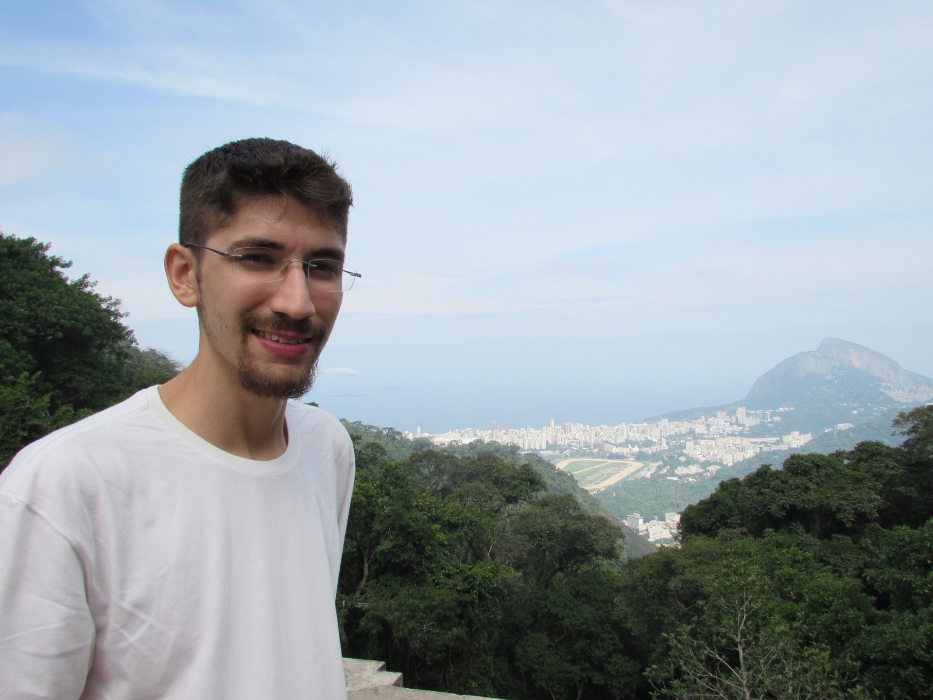 Visitante sorrindo em um mirante do Parque Nacional da Tijuca com a cidade ao fundo