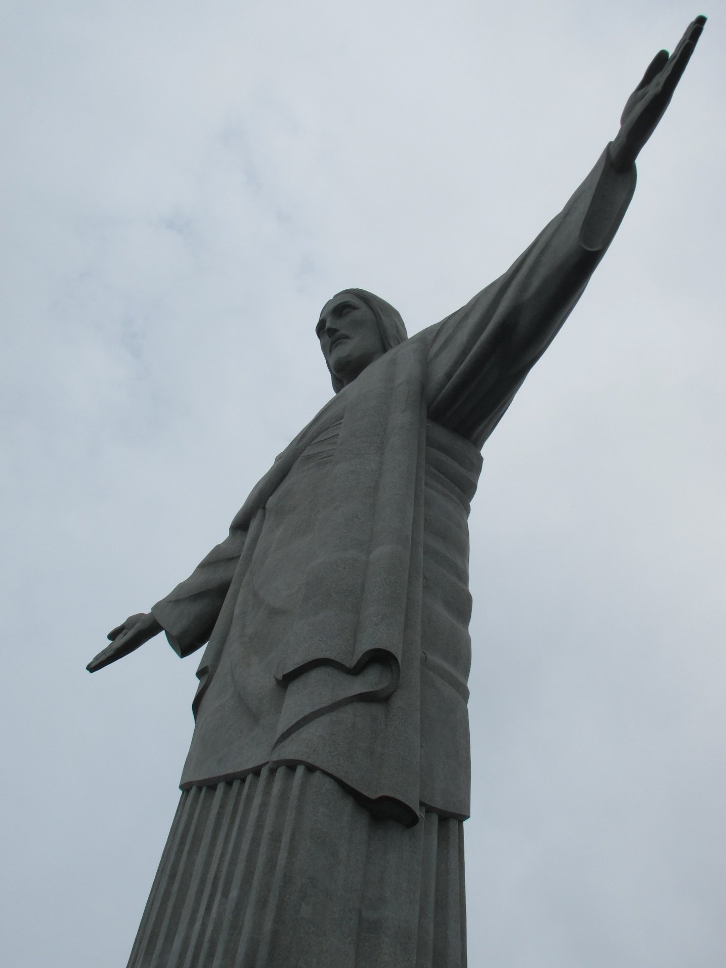 Detalhe do rosto e do braço direito do Cristo Redentor visto de baixo