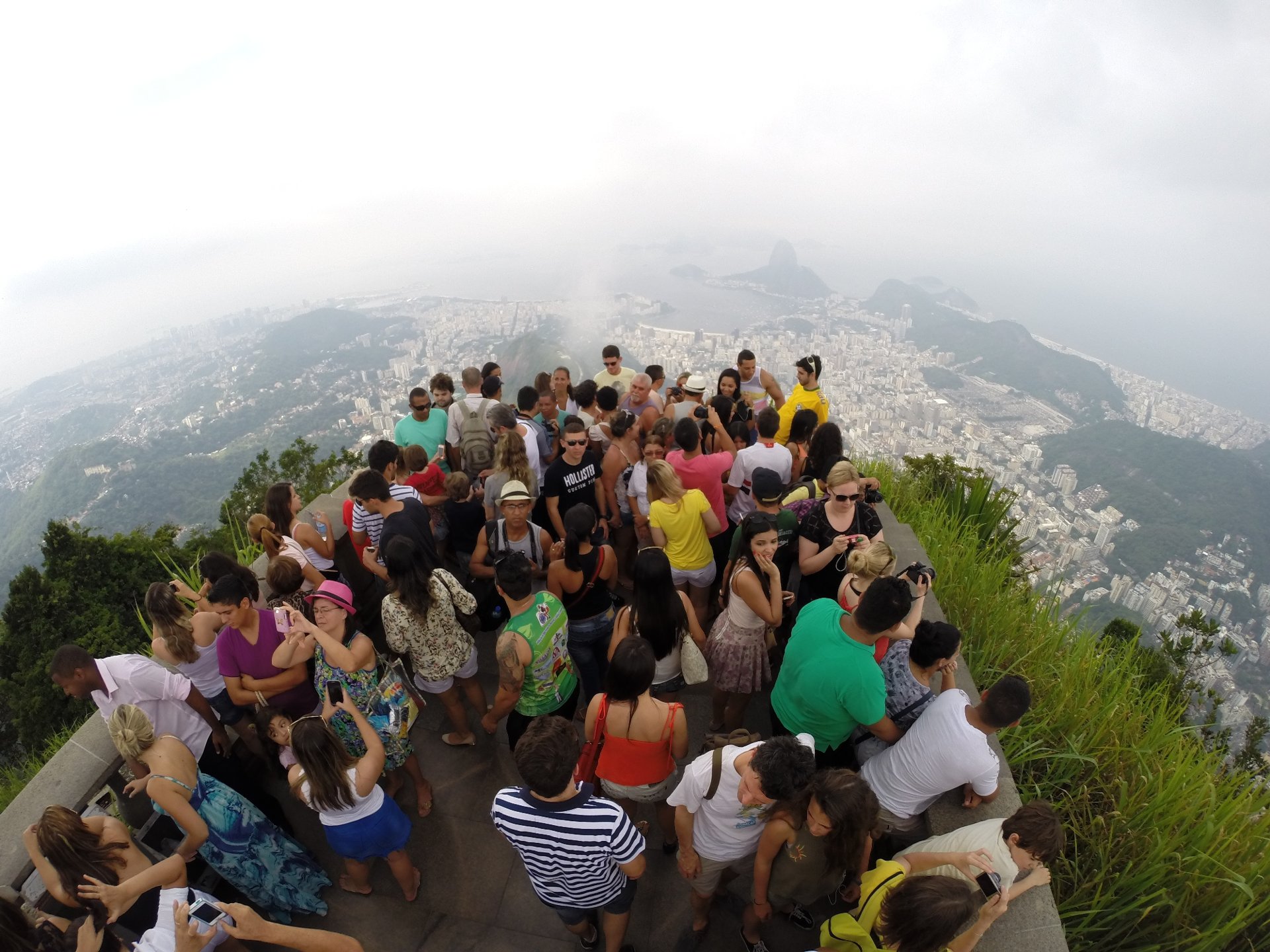 Mirante do Cristo Redentor lotado de visitantes, com a cidade encoberta pela neblina