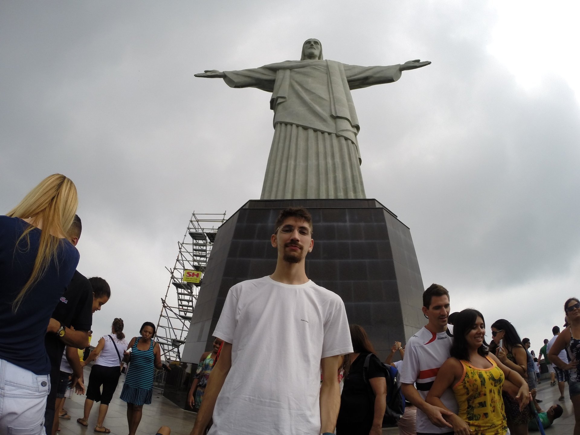 Cristo Redentor em dia nublado, com visitante na base da estátua